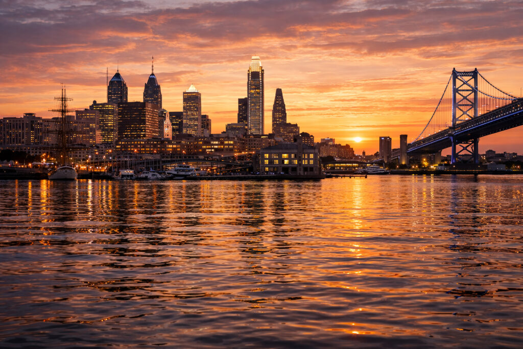 Philadelphia skyline and the Benjamin Franklin Bridge reflected on the Delaware River at sunset