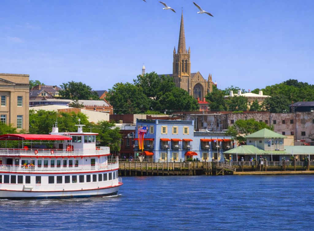 Wilmington Tours riverboat cruising the Cape Fear River with downtown Wilmington waterfront and historic church skyline